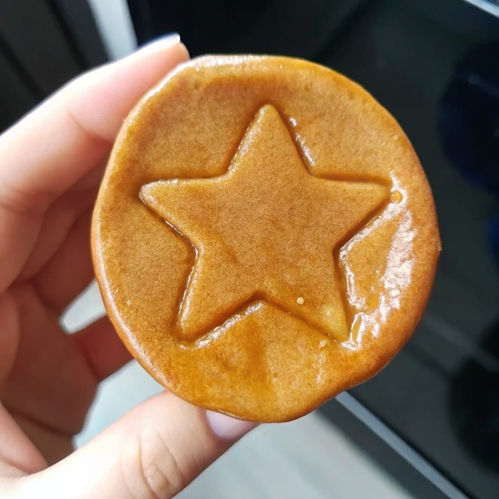 Squid Game Cookie Recipe – Proven Steps for Sweet Victory 6 Flat lay of traditional Korean Dalgona candy (ppopgi) on a parchment-lined tray, with cookie cutters, caramel tones, soft kitchen light, warm aesthetic.